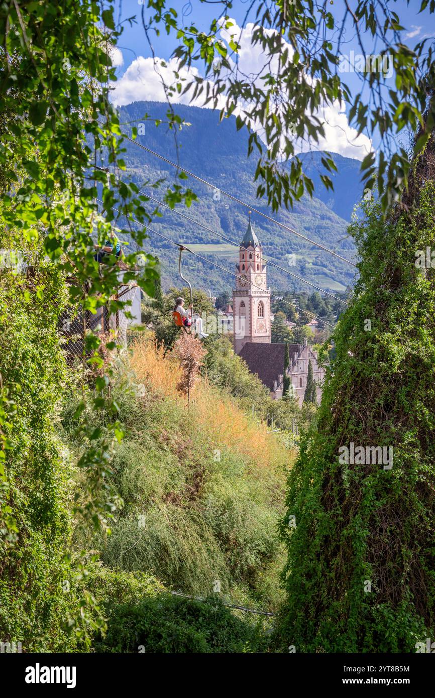 Der Sessellift, der die Stadt Meran mit dem Dorf Tirol verbindet, im Hintergrund die Pfarrkirche St. Nikolaus, Meran, Trentino-Südtirol/Südtirol, Italien Stockfoto
