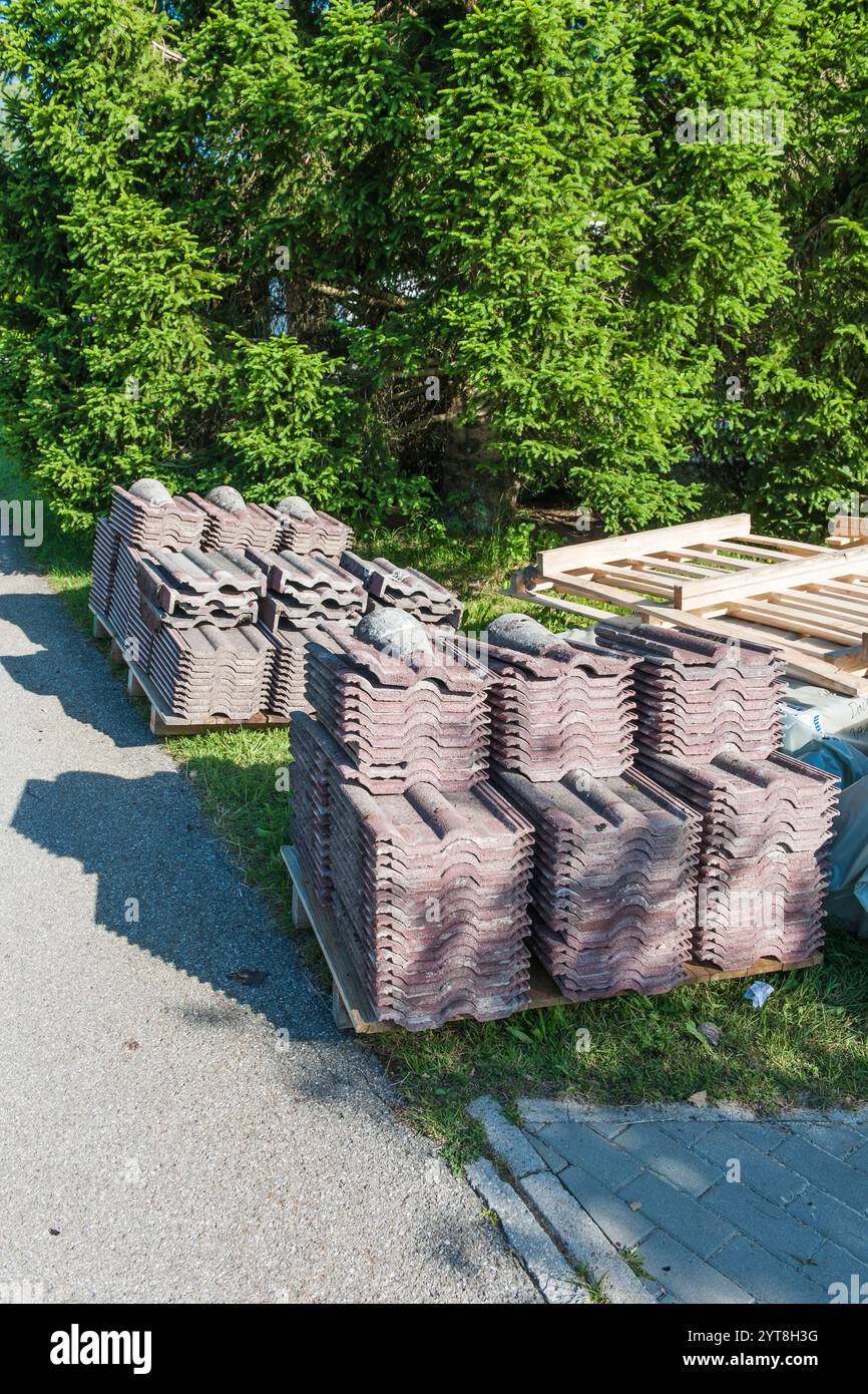 Alte demontierte Dachschindeln, die nach dem Austausch im sonnigen Seitenlicht mit Schatten ordentlich auf Paletten gestapelt sind. Stockfoto