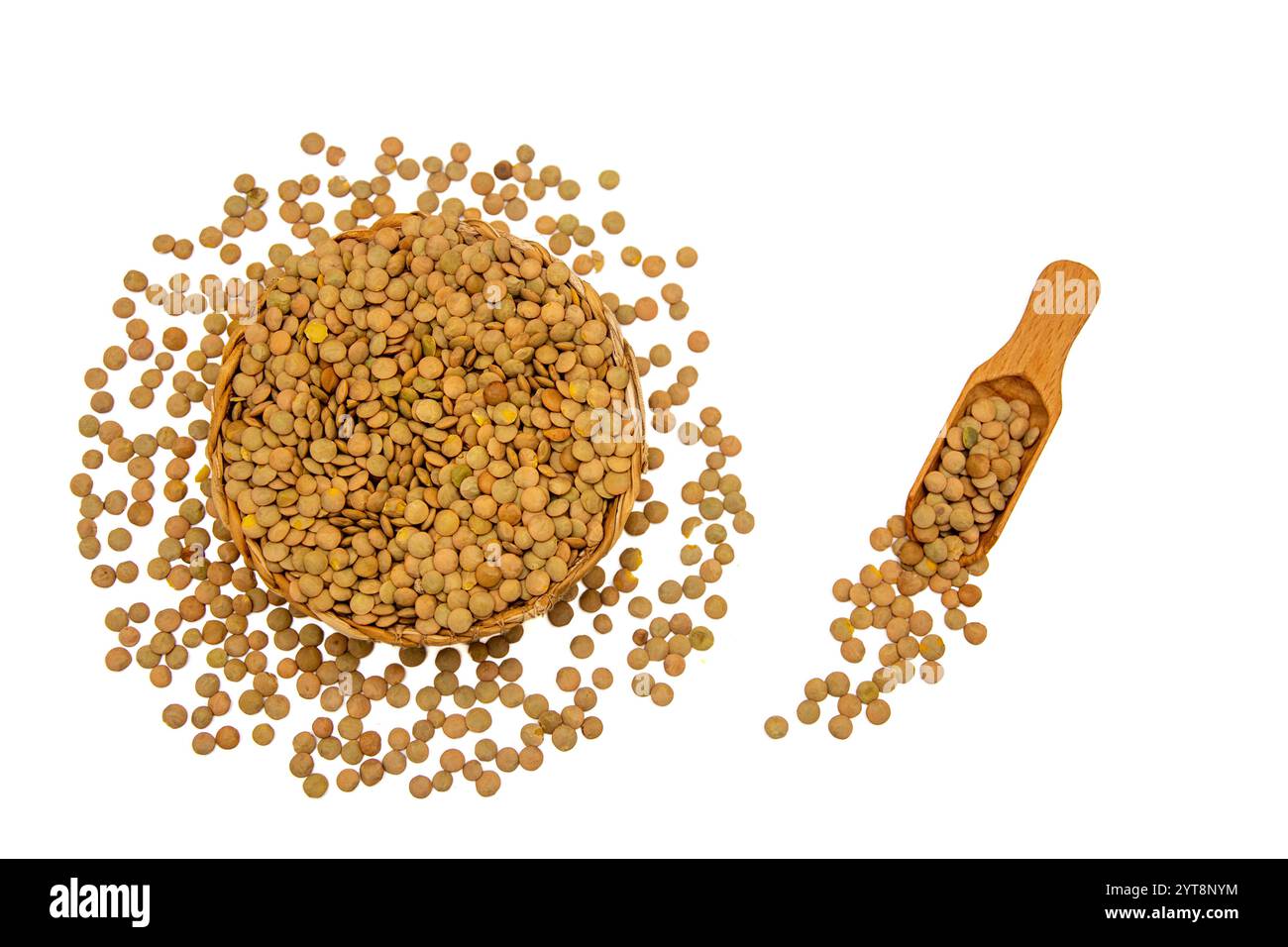 Eine Korbschale gefüllt mit grünen Linsen, begleitet von einem Holzlöffel, umgeben von grünen Linsenkörnern. Stockfoto