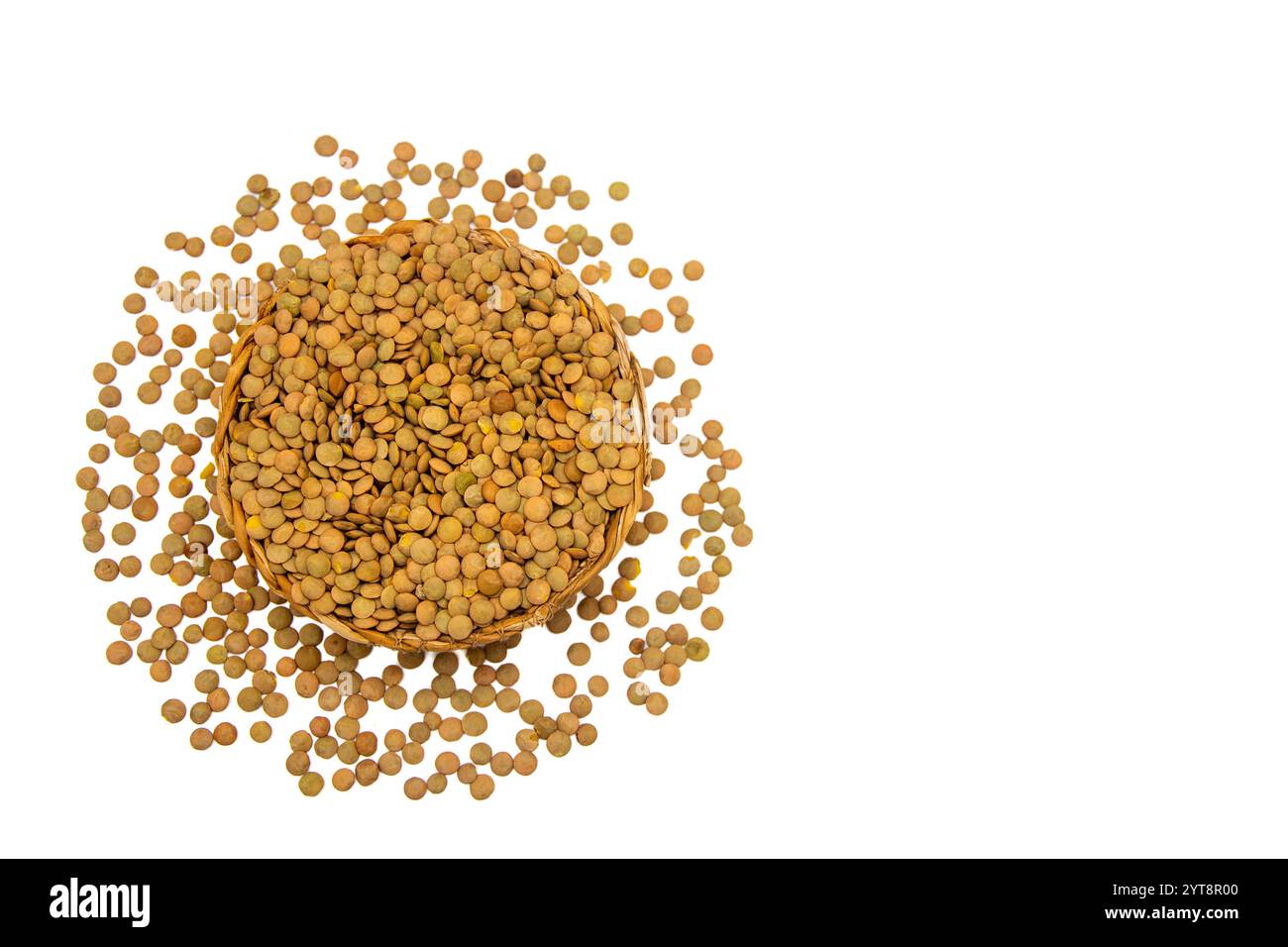 Eine Korbschale gefüllt mit grünen Linsen, umgeben von verstreuten grünen Linsenkörnern. Stockfoto