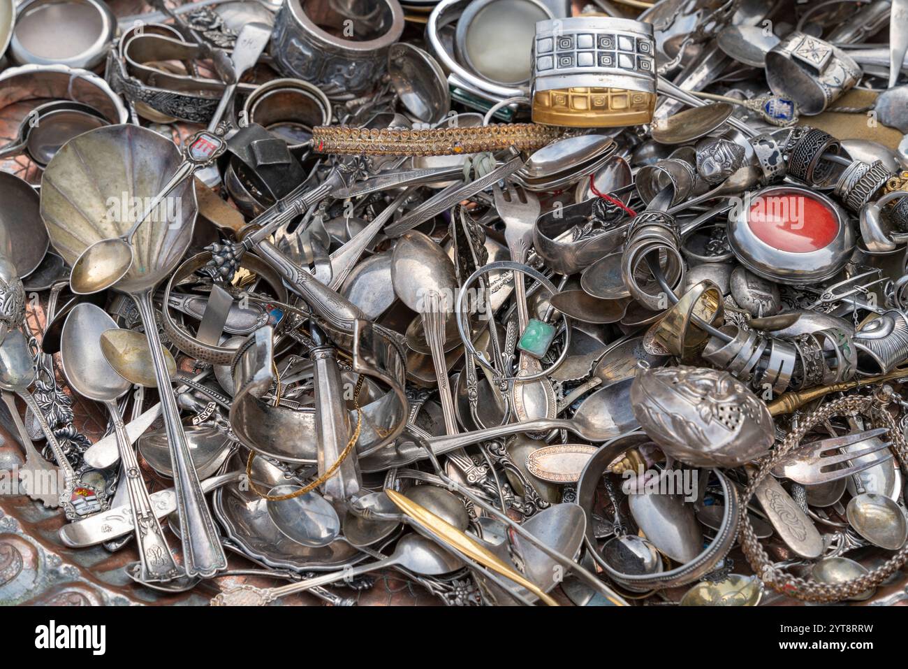 Vollformataufnahme mit vielen angeschmierten, meist silberfarbenen Metallschmuck und Besteck Stockfoto