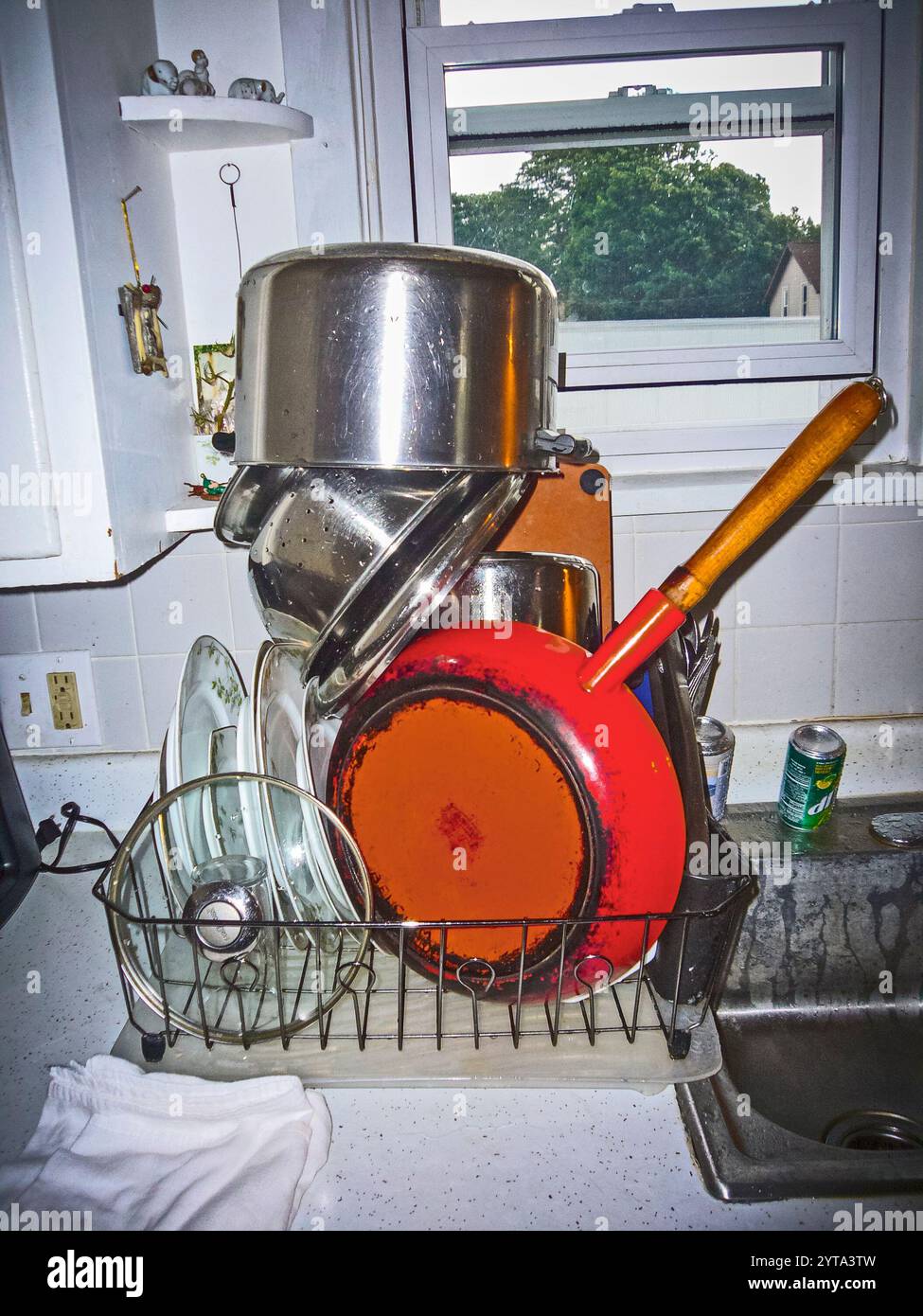 Gekonnt stapeltes Geschirr mit einer großen orangen belgischen Bratpfanne auf dem Trockenregal in einer Küche in Ludington, Michigan, USA. Stockfoto