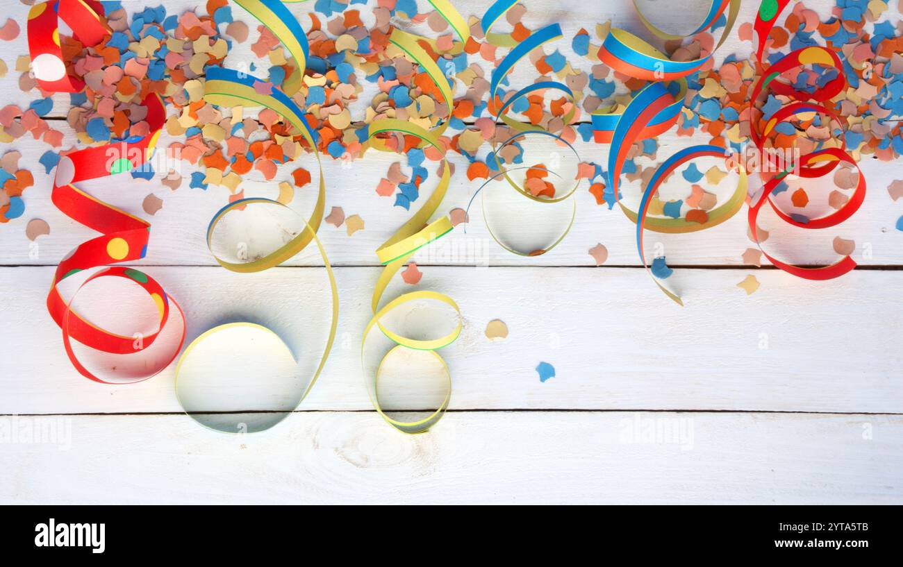 Das farbenfrohe, Luftschlangen und Konfetti auf weißem Holz für Karneval und Party Stockfoto