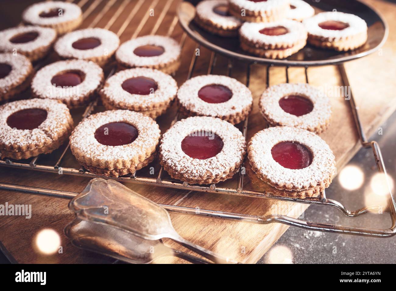 Traditionelle Linzer Plätzchen mit Johannisbeermarmelade frisch aus dem Ofen. Hausgemachte österreichische Kekse auf Holzbrett mit stimmungsvollem Bokeh. Stockfoto