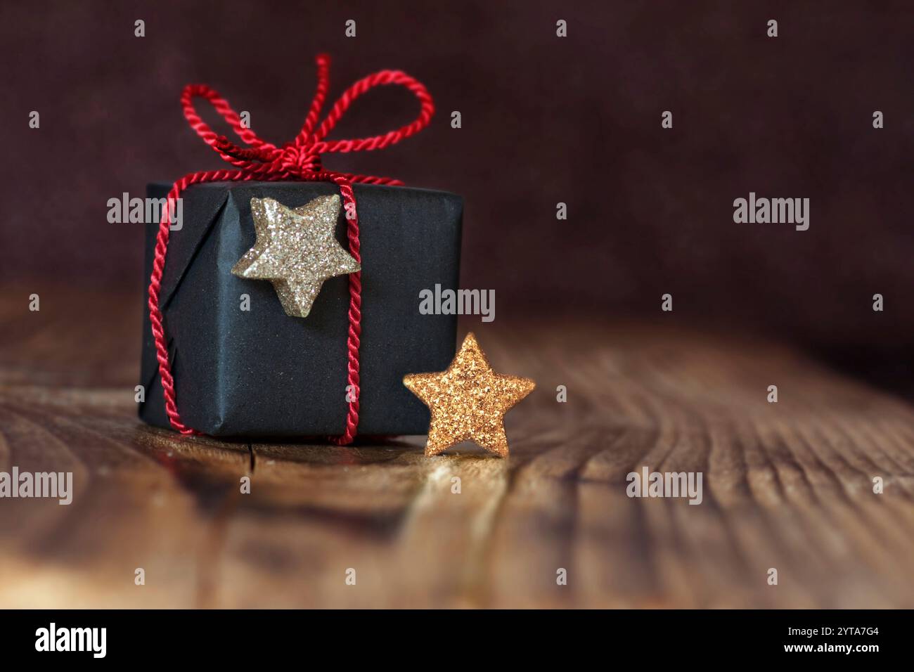 Geschenk für Weihnachten mit rotem Band zwei Sterne in Gold und Silber vor einem dunklen Hintergrund Stockfoto