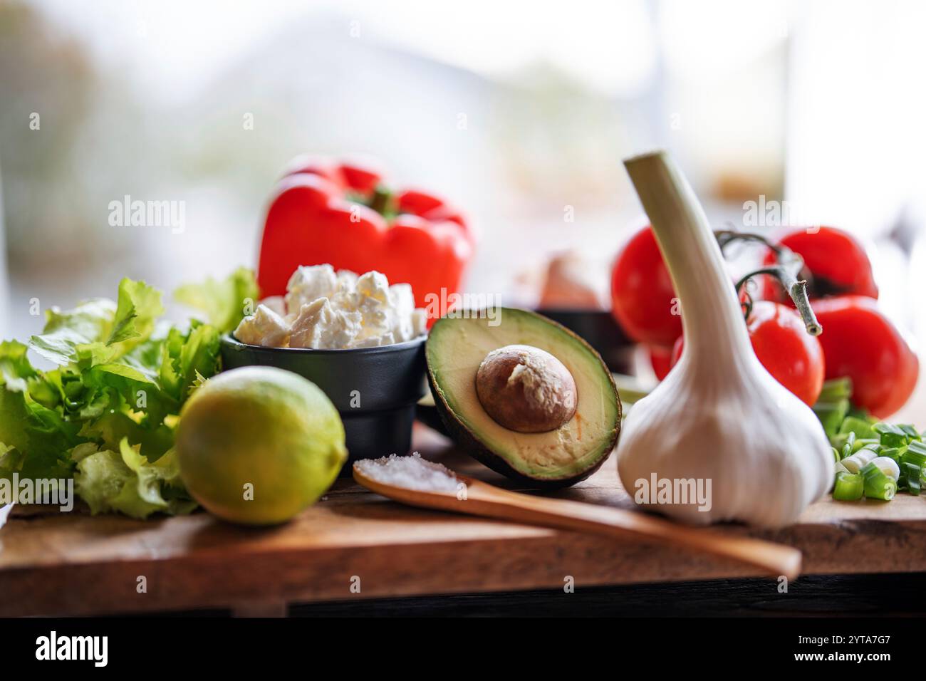 Gesundes Gemüse und frische Zutaten auf hölzernem Schneidebrett vor dem hellen Küchenfenster. Gesundes Nährstoffkonzept für eine Frühlingsdiät. Leerzeichen für Text. Stockfoto