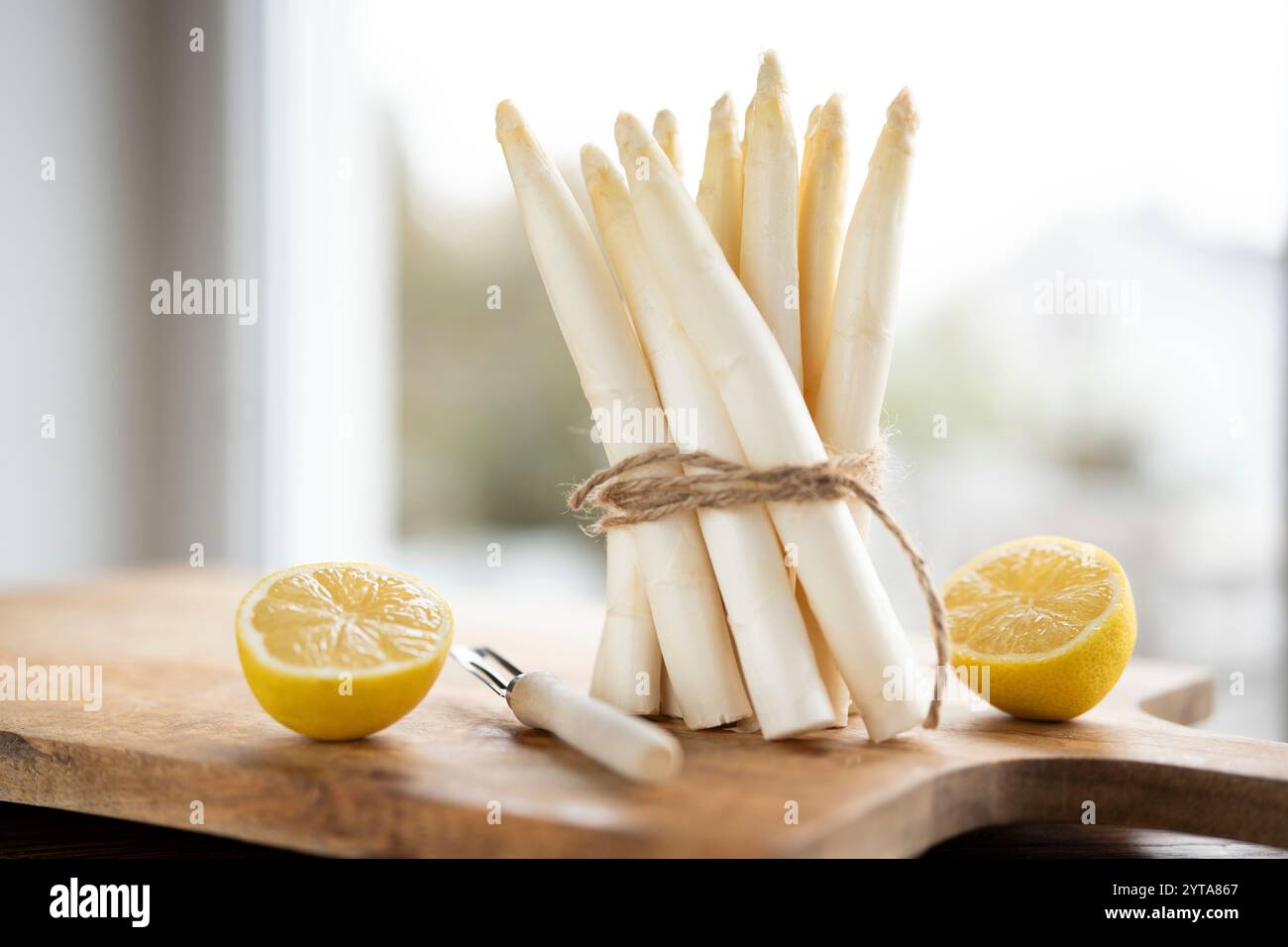 Ein Haufen frischer weißer Spargel. Saisonales Frühlingsgemüse mit Zitrone auf einem hölzernen Schneidebrett. Küche für die saisonale Gastronomie. Stockfoto