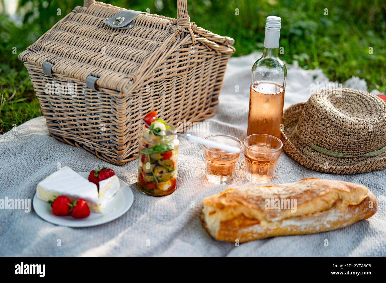 Sommer-Picknick mit köstlichen Speisen und einer Flasche Rosenwein im Grünen. Stockfoto