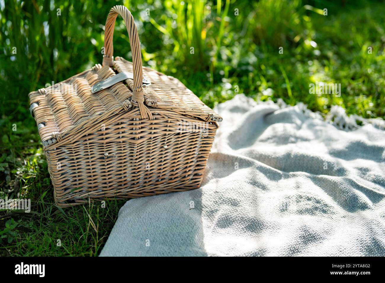 Geschlossener Korb auf Wolldecke. Hintergrund für das Sommer-Picknick im grünen Gras. Stockfoto