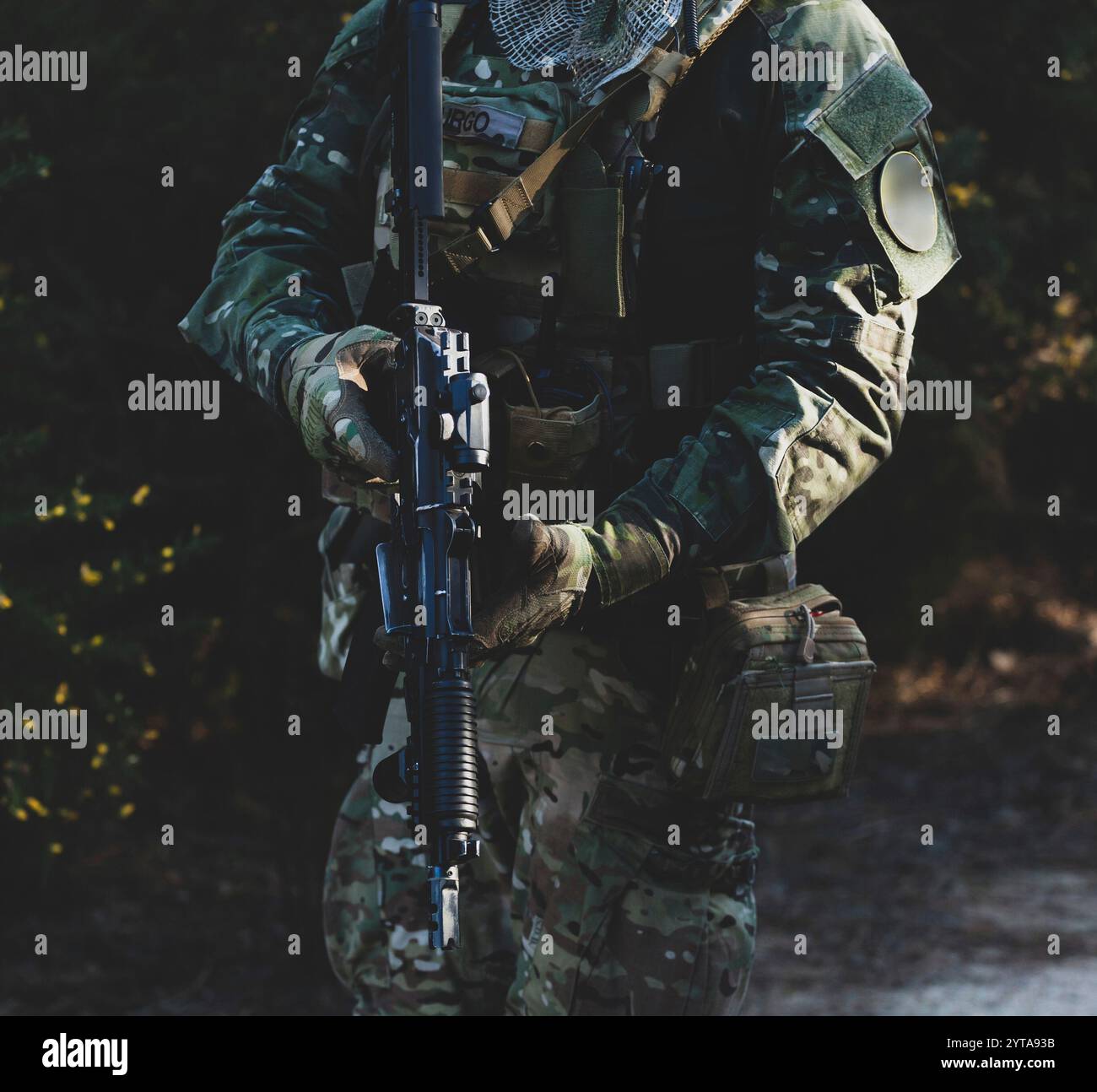 Airsoft-Spieler in Tarnuniform mit bewaffnetem Sturmgewehr Stockfoto