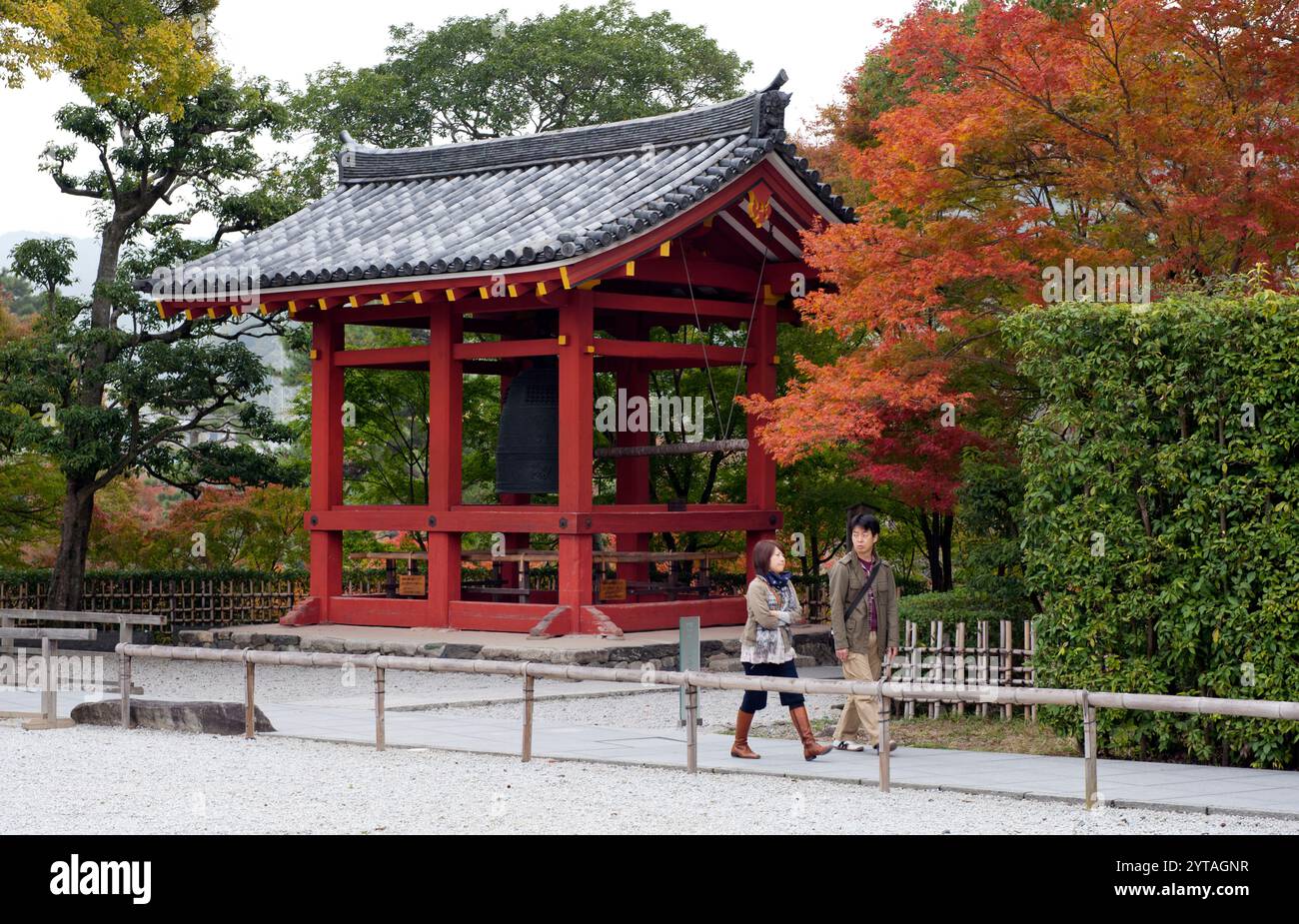 Besucher, die an dem buddhistischen Glockenturm der Jodo-Schule und dem Byodoin-Tempel der Tendai-Schule in Uji-Stadt, Kyoto, Japan, vorbeilaufen. Stockfoto