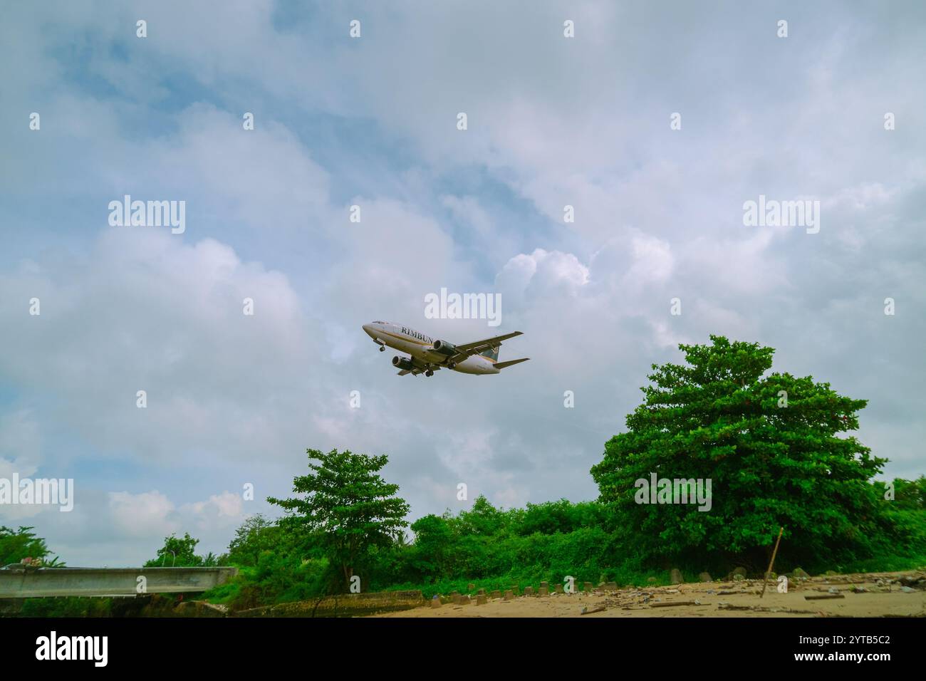 Ein kommerzielles Jet-Flugzeug fliegt tief über dem Strand von Balikpapan, während es landet, am 10. Oktober 2024 in Ostkalimantan, Indonesien Stockfoto