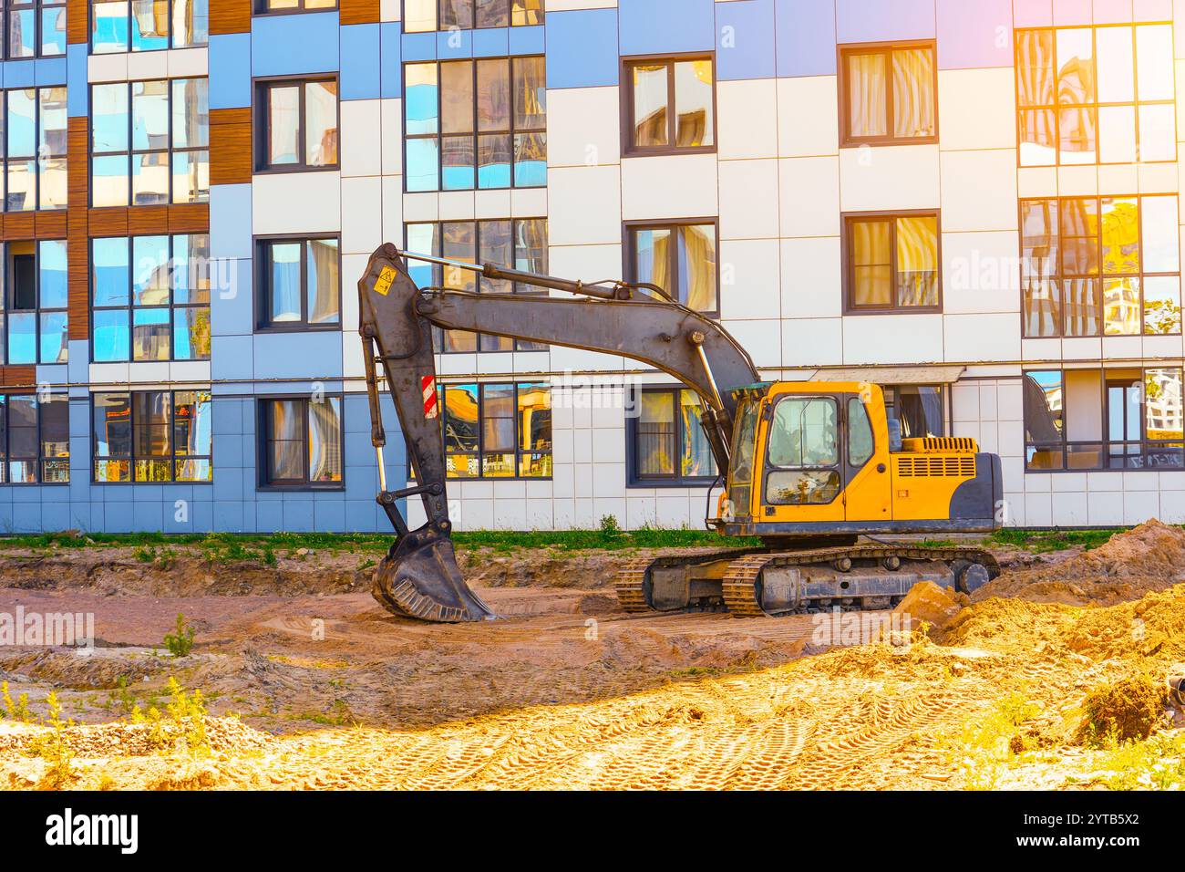 Baggerausrüstung vor dem Hintergrund eines mehrstöckigen Gebäudes. Stockfoto