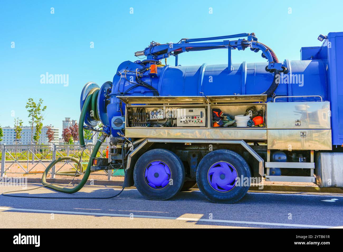 Pumpen von Wasser aus Abwasserkanälen während des Straßenbaus in der Stadt. Fahrzeug mit blauem Wassertank. Stockfoto
