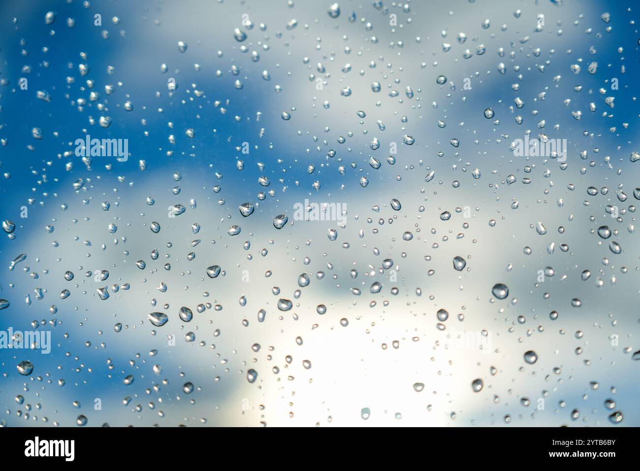 Regen tropft auf das Glas. Wunderschöne blaue und weiße Himmelssonne Stockfoto