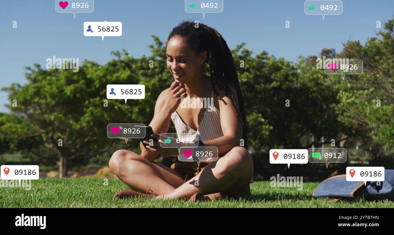 Auf Gras sitzend und mit Smartphone, mag die Frau umgeben von sozialen Medien das Bild Stockfoto