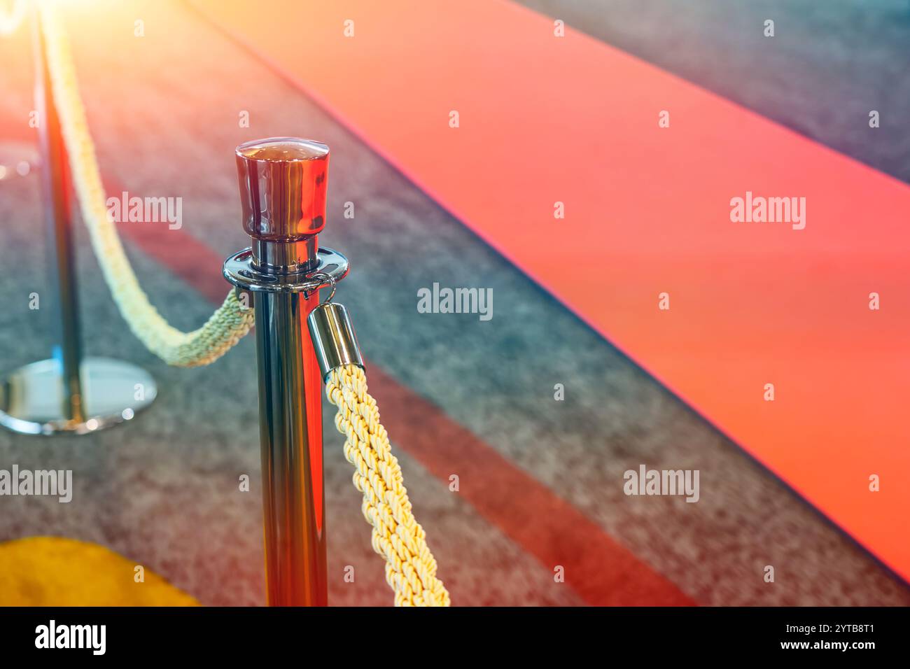 Seilzaun mit goldenen Säulen mit rotem Teppich für Prominente und Gäste einer teuren Veranstaltung mit Menschenmassen Stockfoto