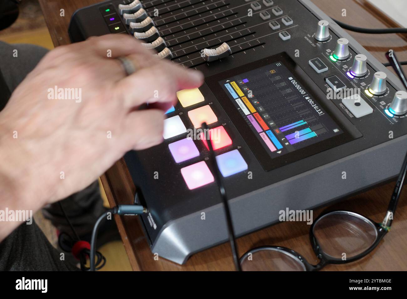 Die Hände eines Mannes, der ein Mischpult bedient, das eingehendes Material mit anderen Klängen über Mikrofone mischen und aufnehmen kann. Nützlich für Podcaster, Streamer Stockfoto