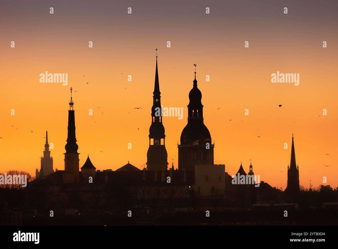 Eine wunderschöne Rigaer Stadtlandschaft während des farbenfrohen Sonnenaufgangs. Gebäude vor buntem Himmel. Nordeuropäischer Morgen mit warmem Himmel. Stockfoto