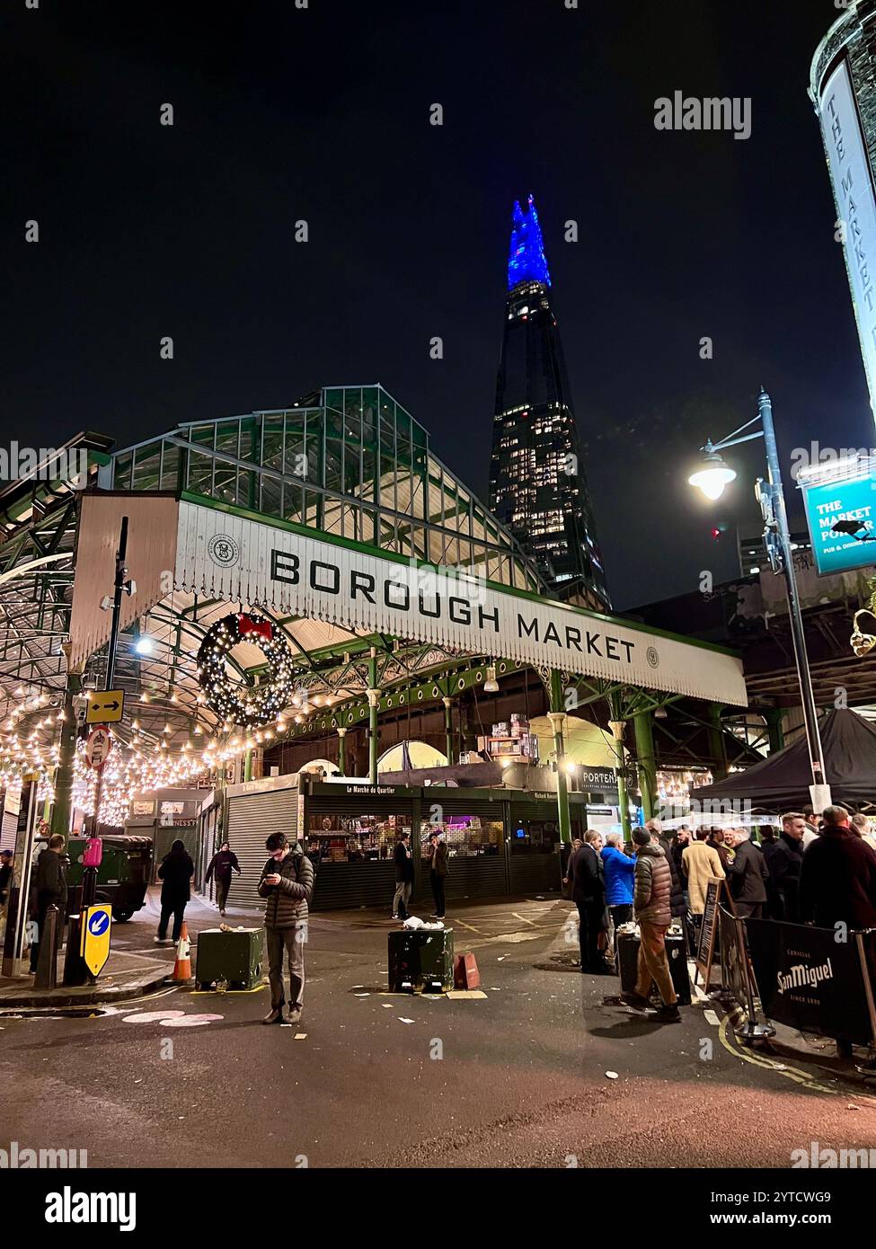 Borough Market London bei Nacht mit Weihnachtskranz und Lichtern. Die Scherbe leuchtet blau im Hintergrund mit Menschen. Stockfoto