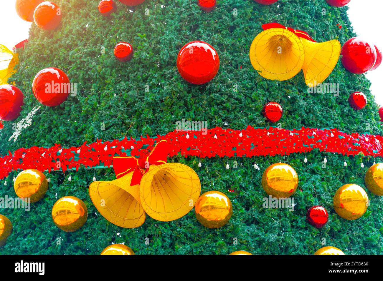 Weihnachtsbaum mit Neujahrsspielzeug, rote Kugeln, glühende Schneeflocken, musikalische Glocken sind das Thema. Stockfoto