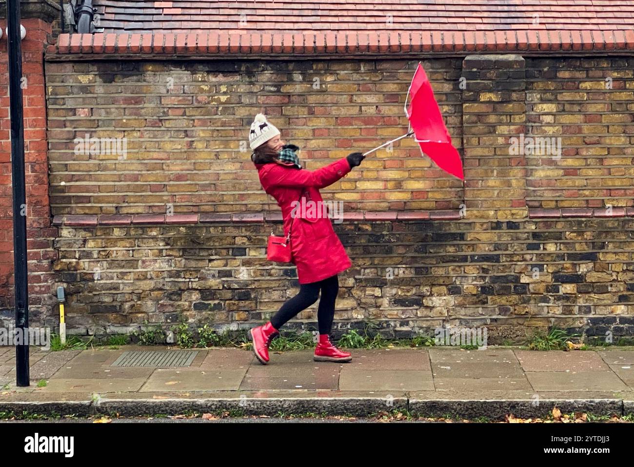 Hammersmith, London, Großbritannien. Dezember 2024. Wetter in Großbritannien: Sturm Darragh bringt Regen und Wind nach Barons Court, London. Im Bild: Raich Keene kämpft unter den Bedingungen mit ihrem Regenschirm. Hinweis: Nidpor/Alamy Live News Stockfoto