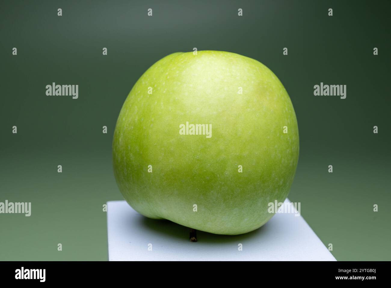 Grüner Apfel auf weiße Erhöhung , Deutschland, 07.12.2024, ein frischer, grüner Apfel auf einer weißen Erhöhung vor einem grünen Hintergrund, symbolisiert gesunde Ernährung und natürliche Lebensmittel. *** Grüner Apfel auf weißer Höhe, Deutschland, 07 12 2024, Ein frischer, grüner Apfel auf weißer Höhe vor grünem Hintergrund, symbolisiert gesunde Ernährung und natürliche Ernährung Stockfoto