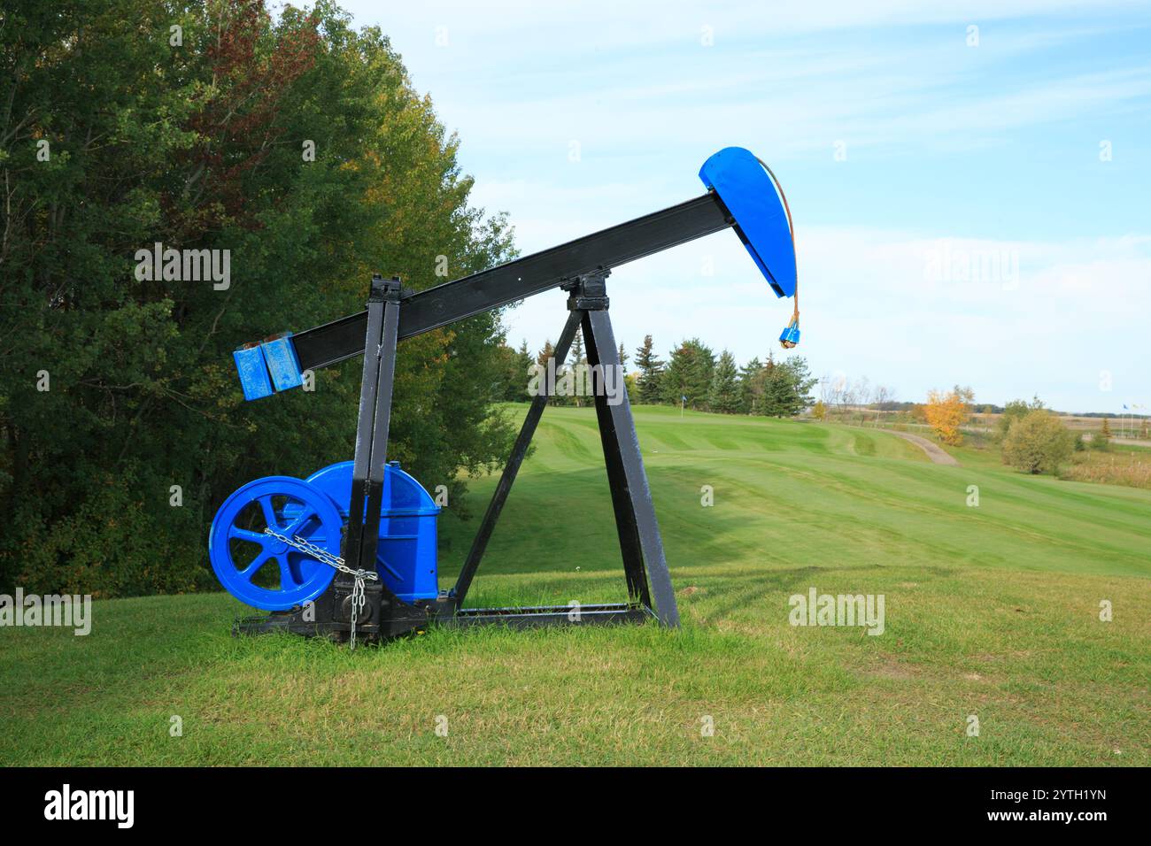 Eine blau-schwarze Ölplattform ist auf einem grasbewachsenen Hügel. Das Bohrfahrzeug ist eine Skulptur und nicht funktionsfähig Stockfoto