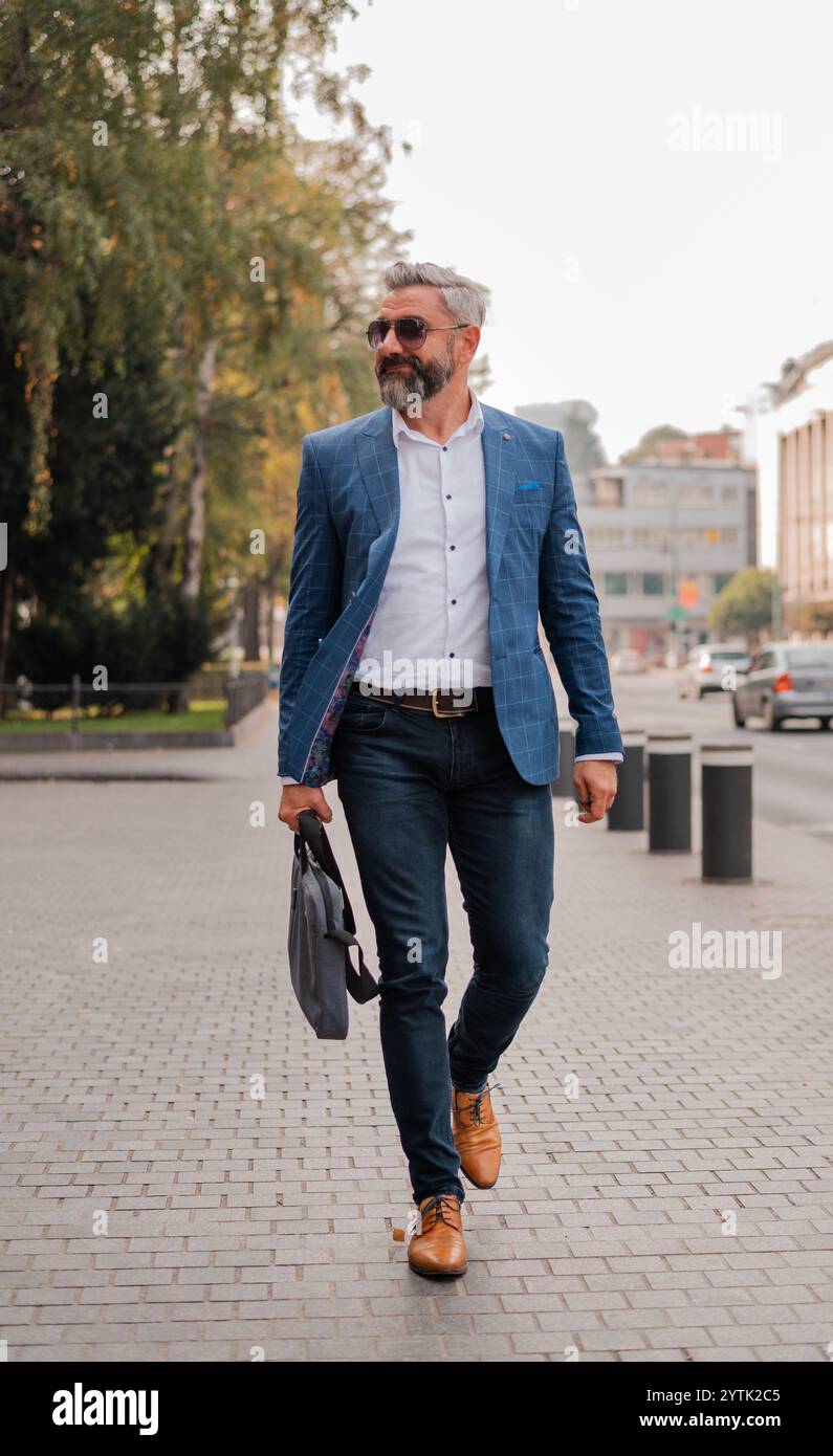 Ein reifer Mann in eleganten, stilvollen Kleidern, der durch die Straße der Stadt spaziert. Hochwertige Fotos Stockfoto