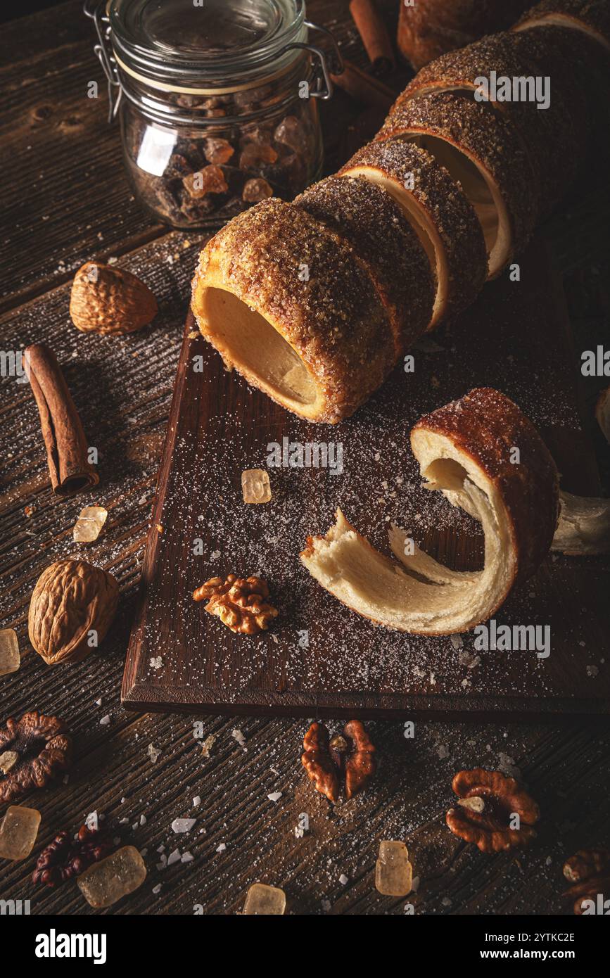 Ungarisches Süßbrot, auf Holzbrett geschnitten, mit Zucker und Walnüssen bestreut, mit Zimtstangen und Steinbonbons Stockfoto