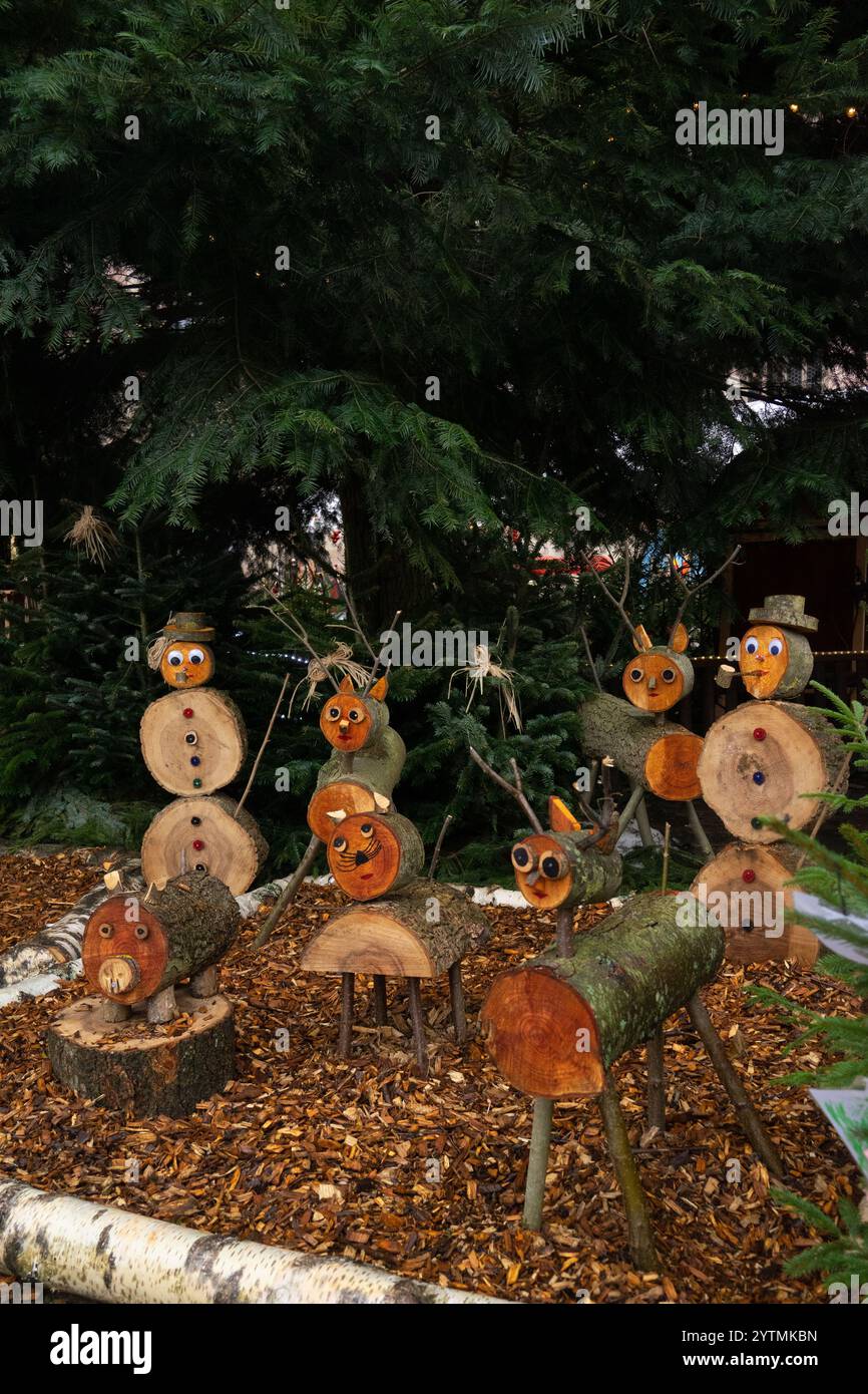 Farbenfrohe Holzfiguren sorgen für eine skurrile Feiertagsplatte in einem gemütlichen Garten und unterstreichen den festlichen Geist Stockfoto