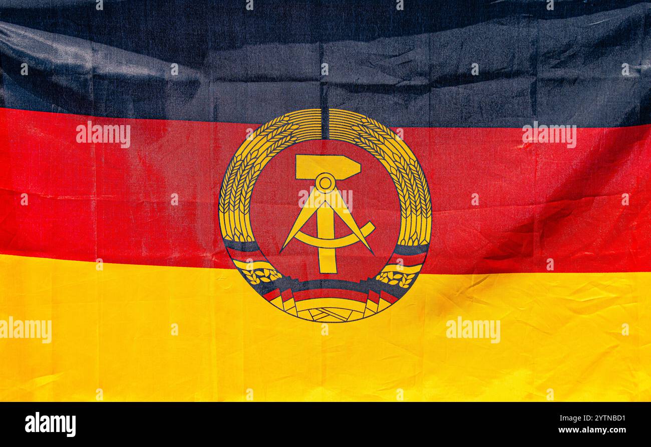 Hüntwangen, Schweiz, 24. August 2024: Die Flagge der DDR mit Hammer, Kompass und Weizenkranz in Schwarz, Rot und Gold. Stockfoto