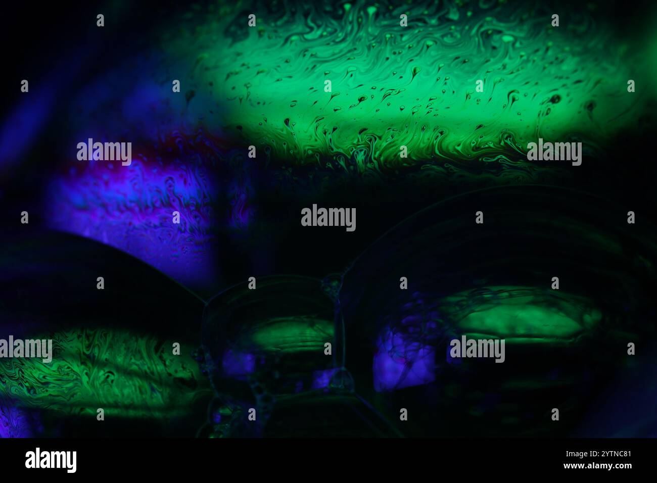 Grüne und lila Fluidplatten, Flüssigkeitsentnahme, Farbwellen, tiefdunkle Hintergründe, glänzende Wasserformen Stockfoto