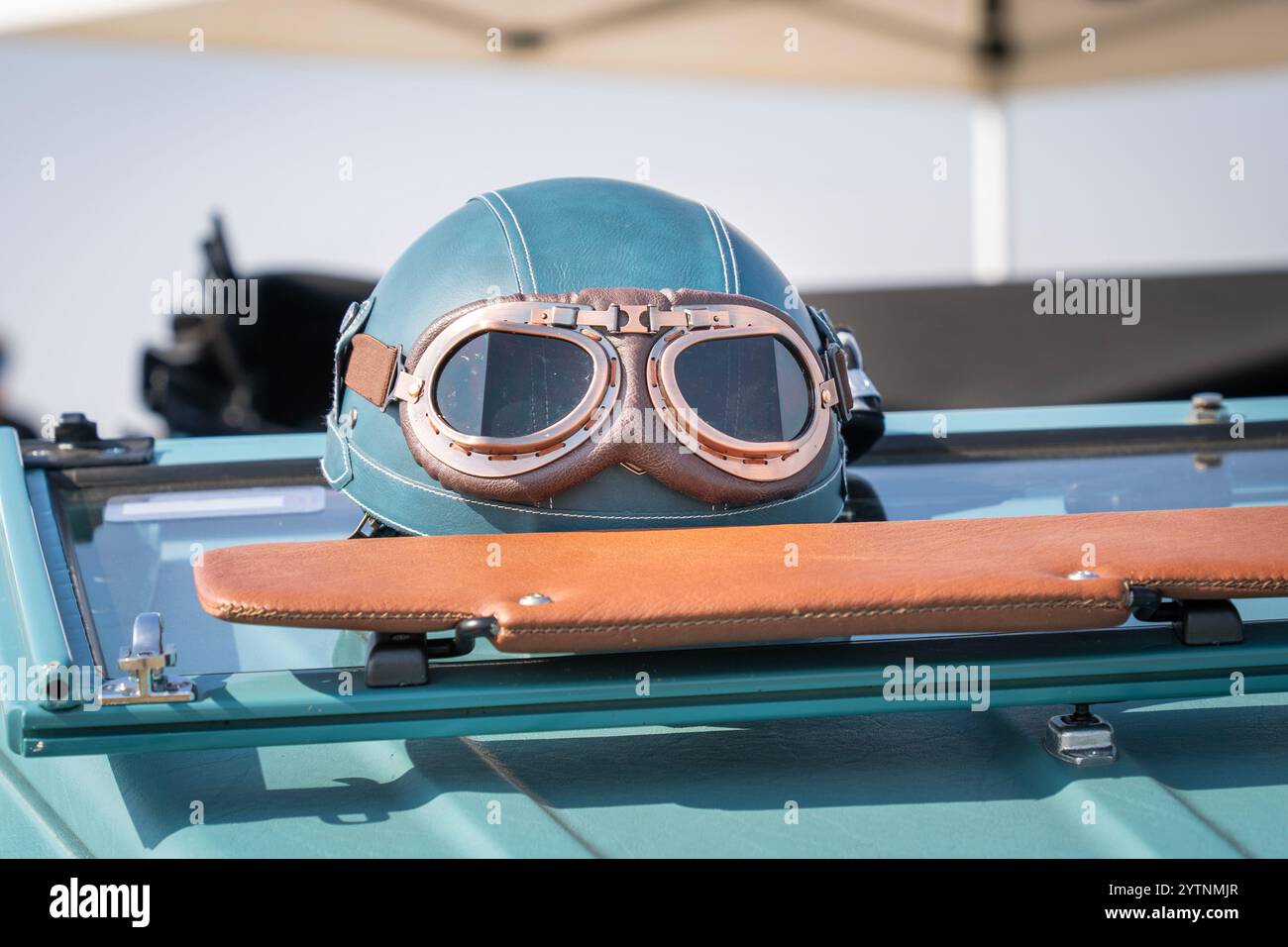 Blaugrüner Oldtimer-Helm und Brille an einem alten Auto Stockfoto
