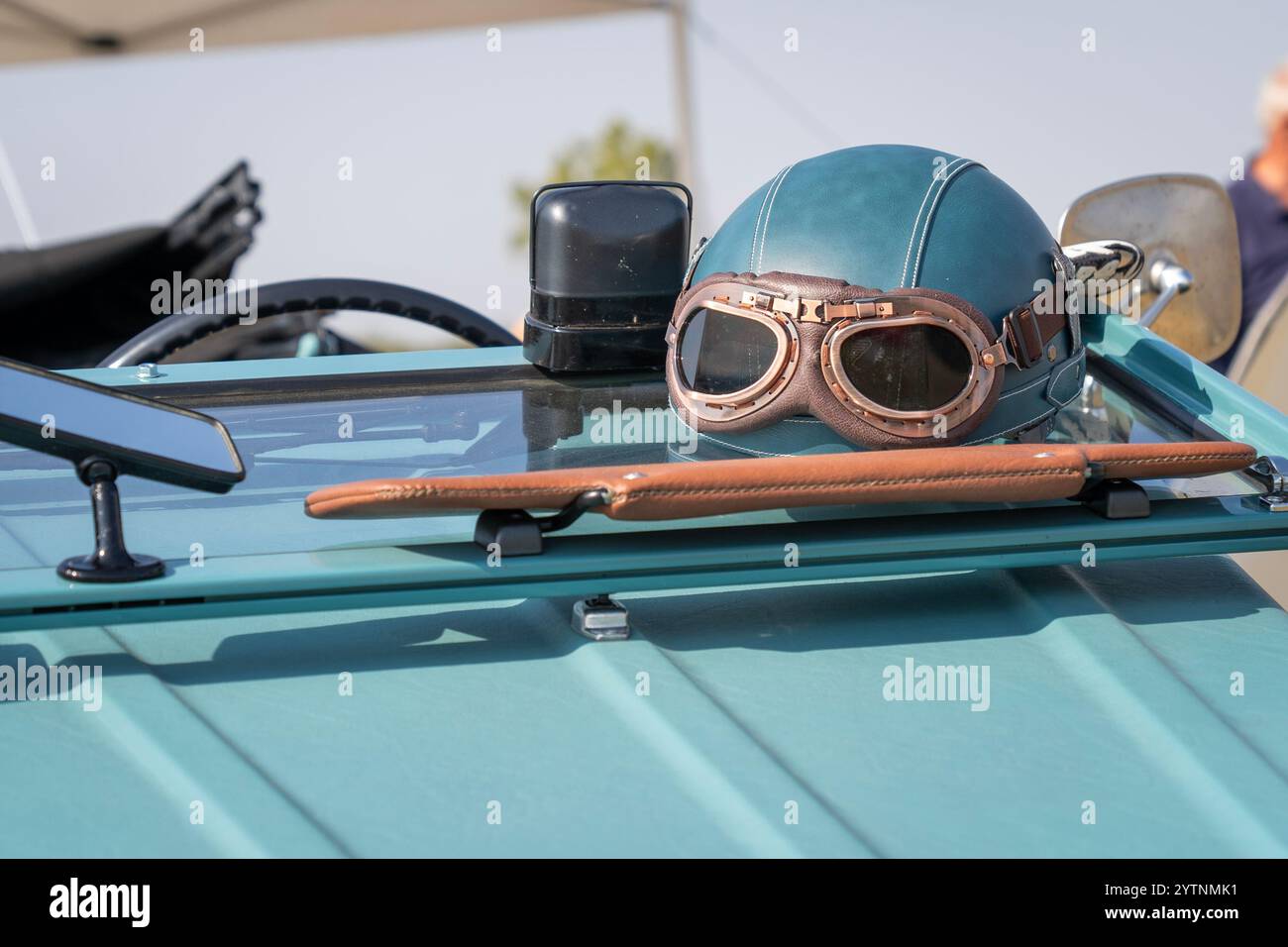 Blaugrüner Oldtimer-Helm und Brille an einem alten Auto Stockfoto