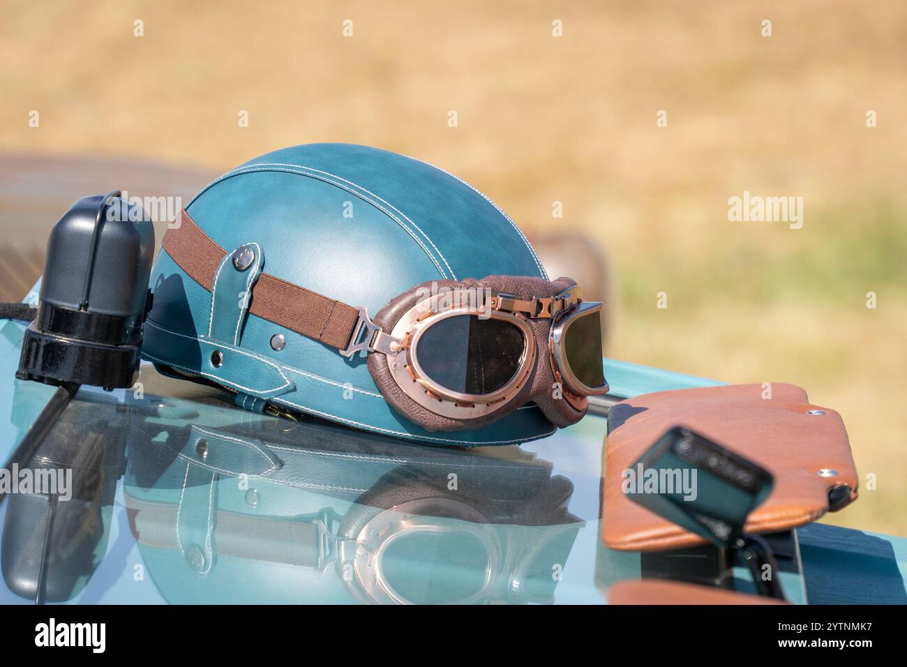 Blaugrüner Oldtimer-Helm und Brille an einem alten Auto Stockfoto