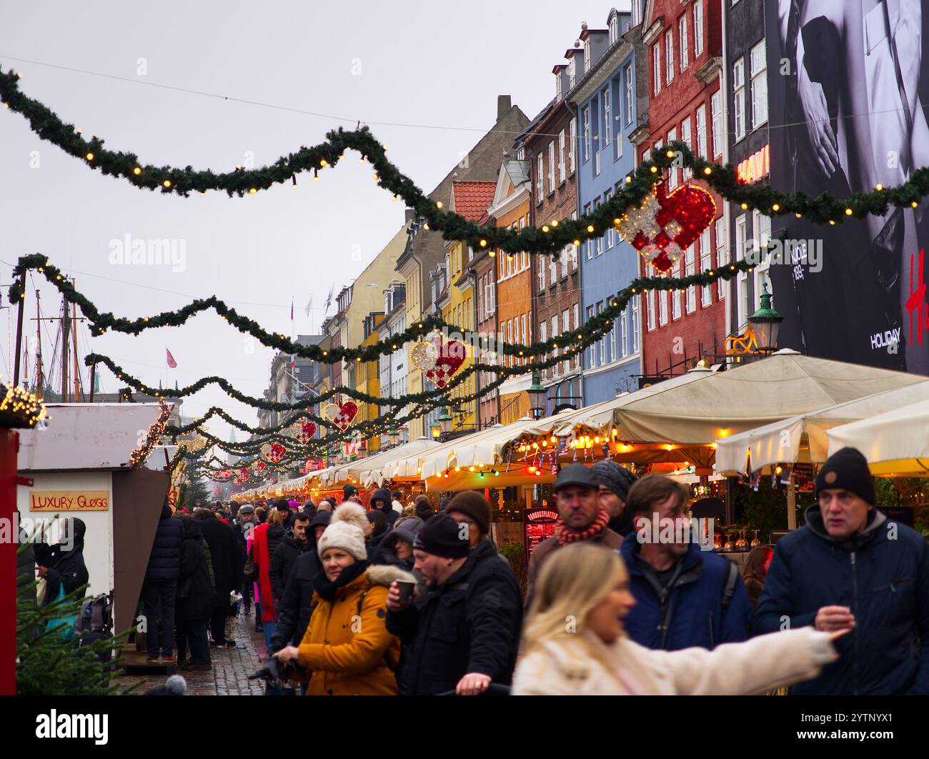 Kopenhagen, Dänemark - 10. Dezember 2023: Überfüllte, dekorierte Nyhavn-Straße mit Fußgängern, die spazieren gehen und weihnachtliche Atmosphäre mit Dekorationen genießen Stockfoto