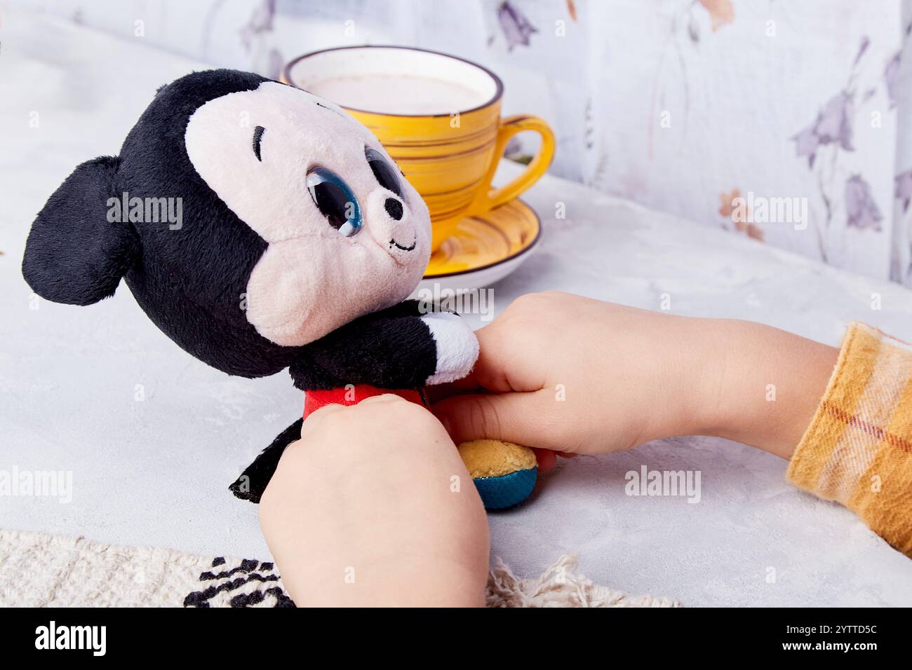 Das Kind hält die ikonische mickey Maus Plüsch - zeitlose Kinderfreude. Stockfoto