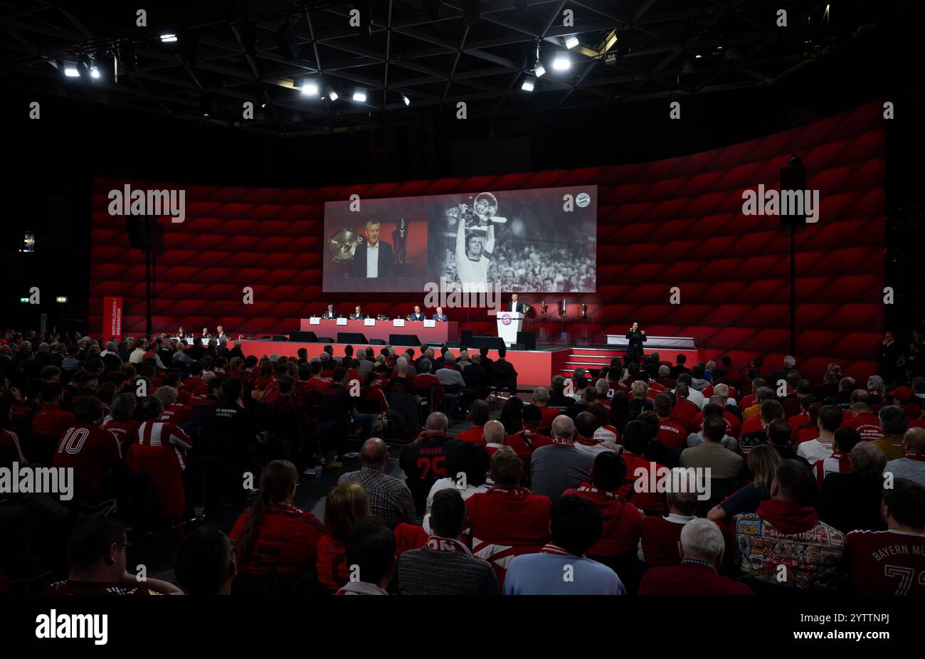 8. Dezember 2024, Bayern, München: Fußball: Bundesliga, Jahreshauptversammlung des FC Bayern München in der Rudi-Sedlmayer-Halle. Herbert Hainer, Präsident von München, steht auf der Bühne. Im Hintergrund ist ein Bild von Franz Beckenbauer zu sehen. Beckenbauers Trikot Nummer 5 wird künftig nicht mehr vergeben. Foto: Sven Hoppe/dpa Stockfoto