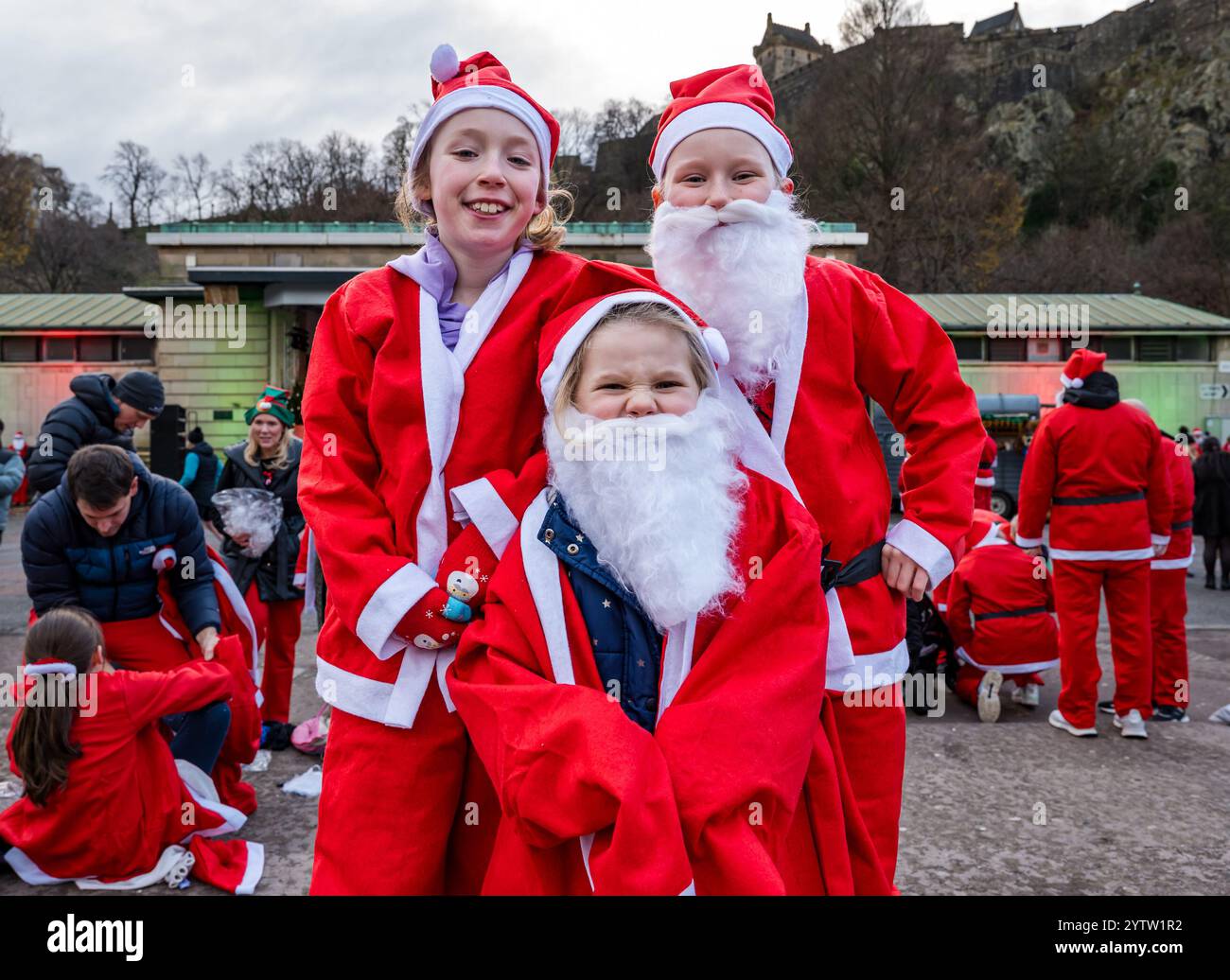 Edinburgh, Schottland, Vereinigtes Königreich, 8. Dezember 2024. Christmas Santa Run: Der Edinburgh Santa Fun Run & Walk feiert 20 Jahre Laufen, Joggen oder Wandern auf einer 2,5 km langen Strecke in den West Princes Street Gardens. Die Veranstaltung sammelt Geld für When you Wish Upon a Star. Im Bild: Die jungen Mädchen Paige (Mitte), Leah & Holly sind begeistert vom Lauf und dem Tragen ihrer Weihnachtsmannkostüme. Quelle: Sally Anderson/Alamy Live News Stockfoto