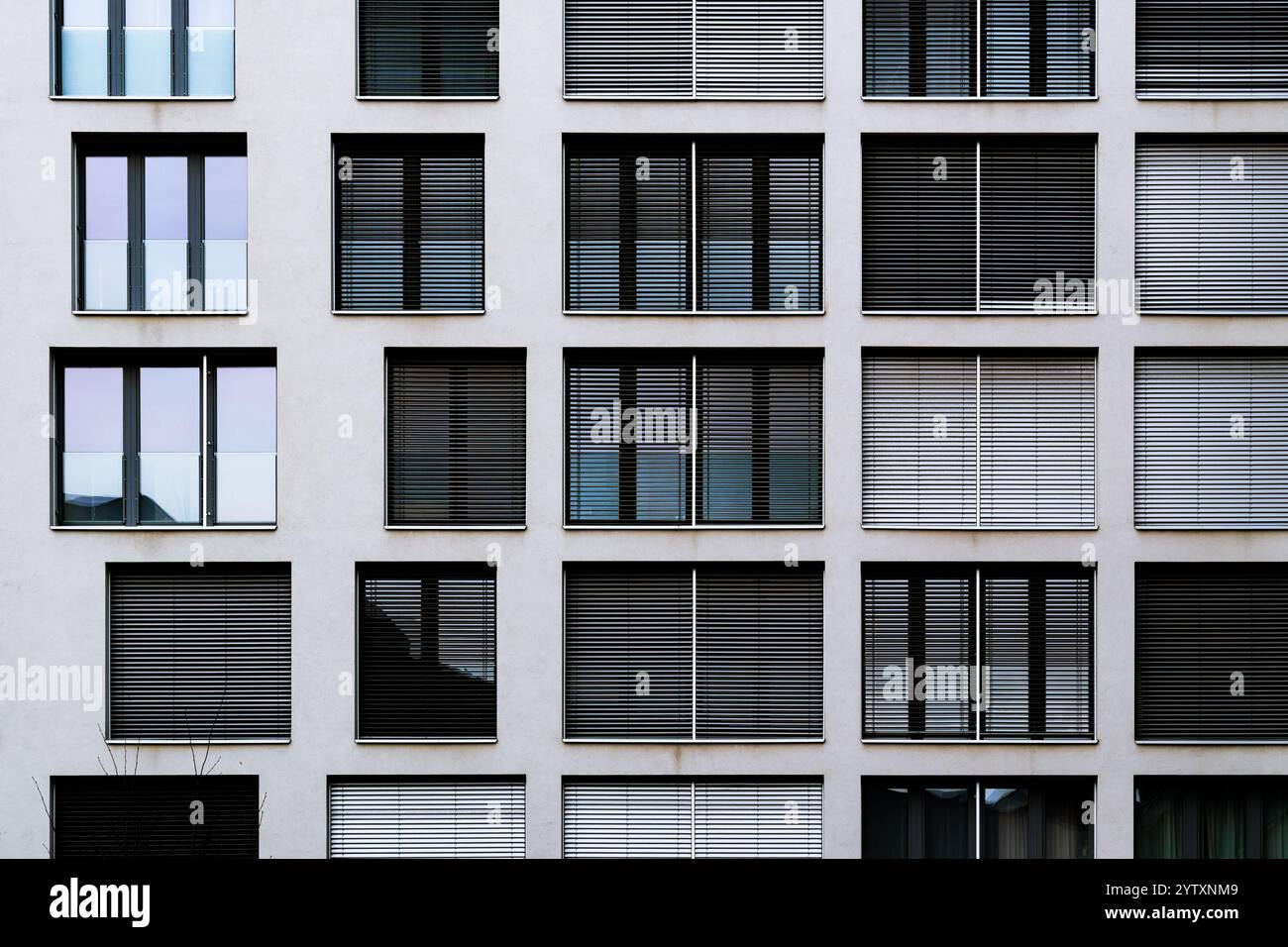 Moderne Gebäudefassade mit symmetrischen Fenstern und horizontalen Jalousien in minimalistischem Design Stockfoto
