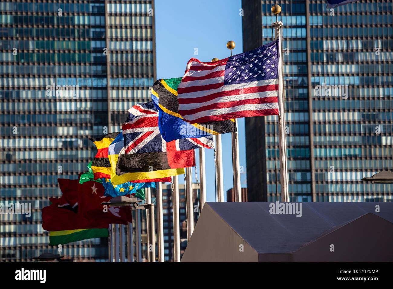 Das Hauptquartier der Vereinten Nationen in New York City mit Beflaggung. Im Vordergrund die Fahne der USA. Stockfoto
