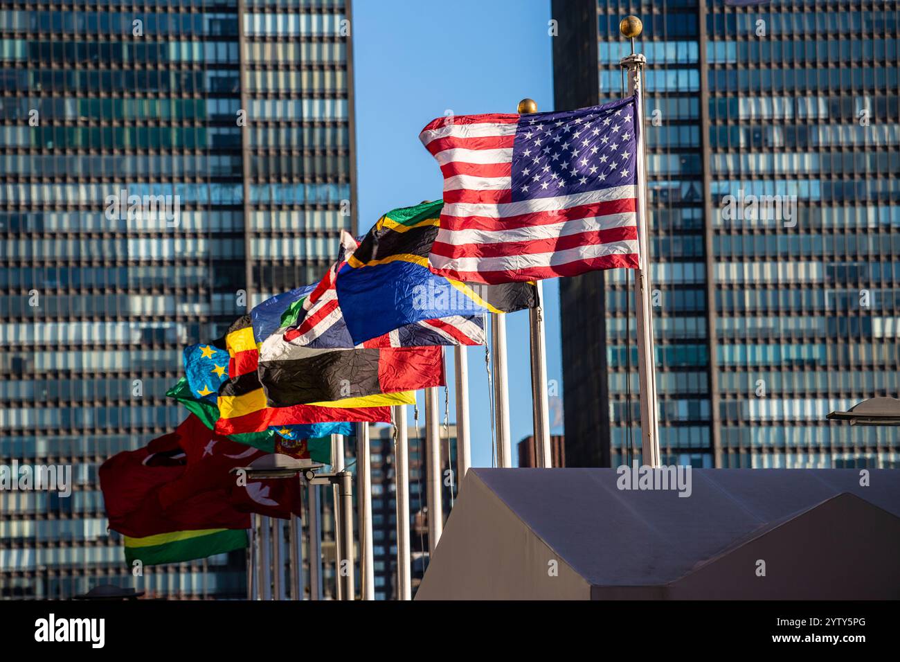 Das Hauptquartier der Vereinten Nationen in New York City mit Beflaggung. Im Vordergrund die Fahne der USA. Stockfoto