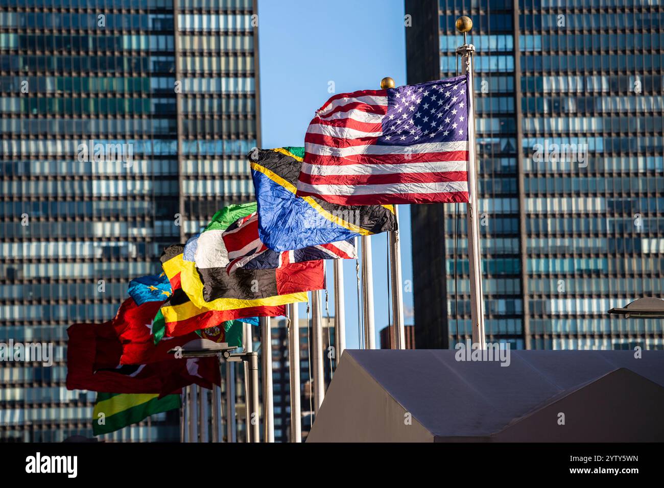 Das Hauptquartier der Vereinten Nationen in New York City mit Beflaggung. Im Vordergrund die Fahne der USA. Stockfoto