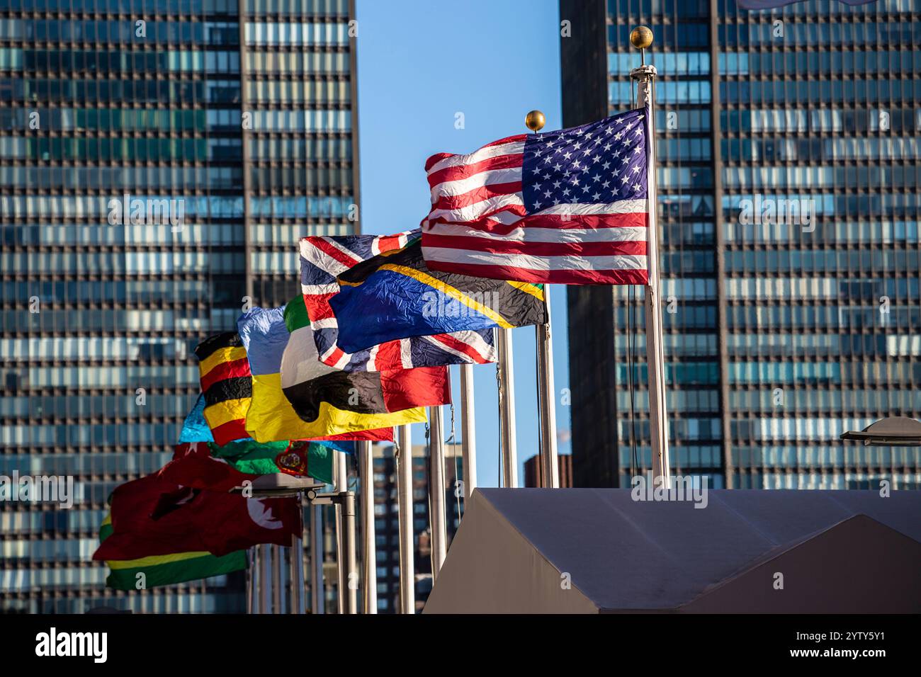 Das Hauptquartier der Vereinten Nationen in New York City mit Beflaggung. Im Vordergrund die Fahne der USA. Stockfoto