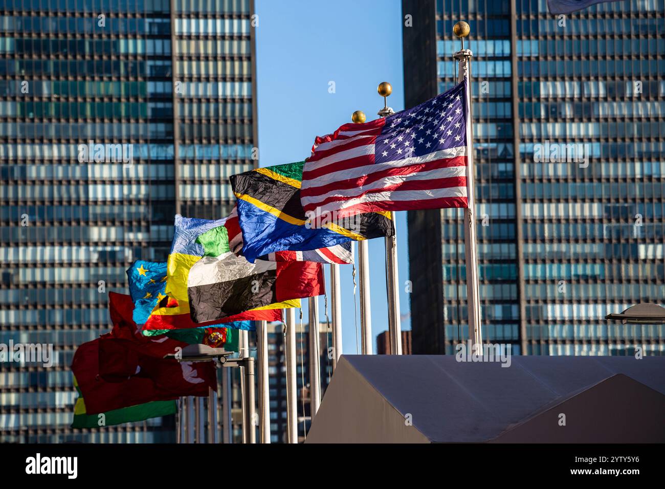 Das Hauptquartier der Vereinten Nationen in New York City mit Beflaggung. Im Vordergrund die Fahne der USA. Stockfoto