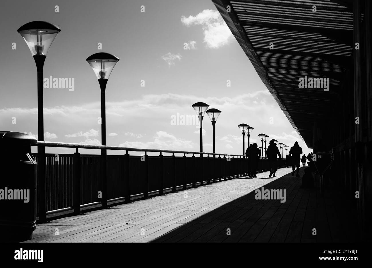 Blick auf den Boscombe Pier mit Menschen, die in der Sonne spazieren gehen, Laternen und Straßenlaternen, Boscombe, Bournemouth, Großbritannien Stockfoto