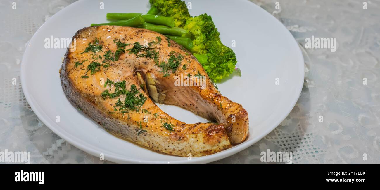 Im Ofen gebackener norwegischer Atlantischer Lachs. Lachs mit Kräutern und gekochtem Gemüse auf einem weißen Teller mit Salat und Sauerkohl. Stockfoto