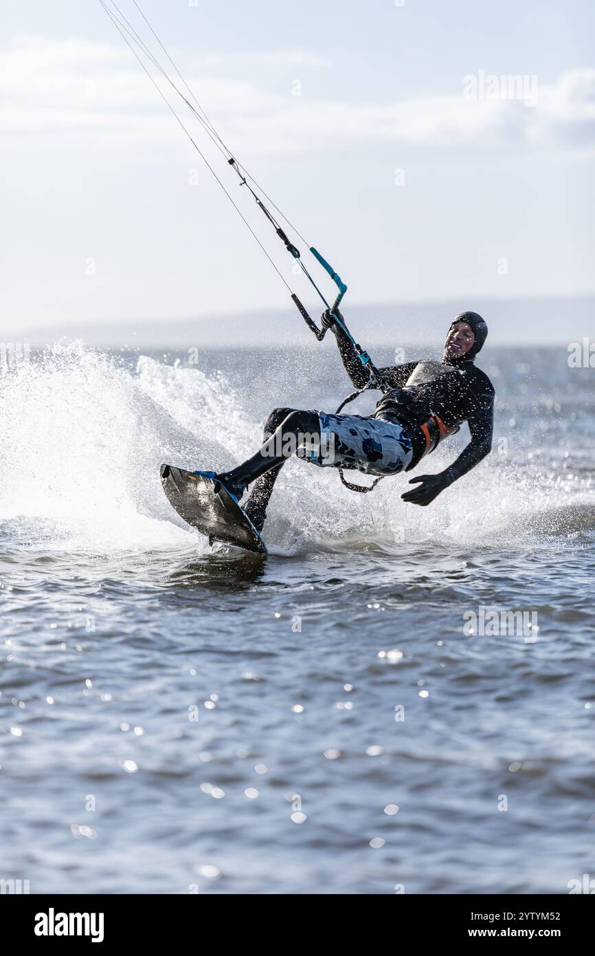 Kitesurfer gleiten mit hoher Geschwindigkeit. Ein Drachenboarder im Meer. Männer in schwarzen Neoprenanzügen gehen Kitesurfen. Extremsport, Kiteboarding. Editorial-Okt. 30 Stockfoto