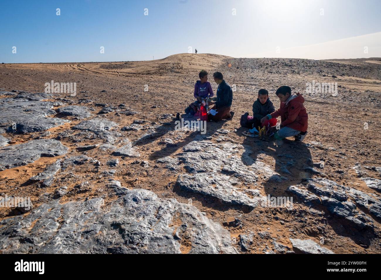 Einige Kinder bereiten ihren improvisierten Markt an einem Fossiliengelände in der marokkanischen Wüste vor. Es sind kleine Kaufleute, die mit Touristen leben. Stockfoto